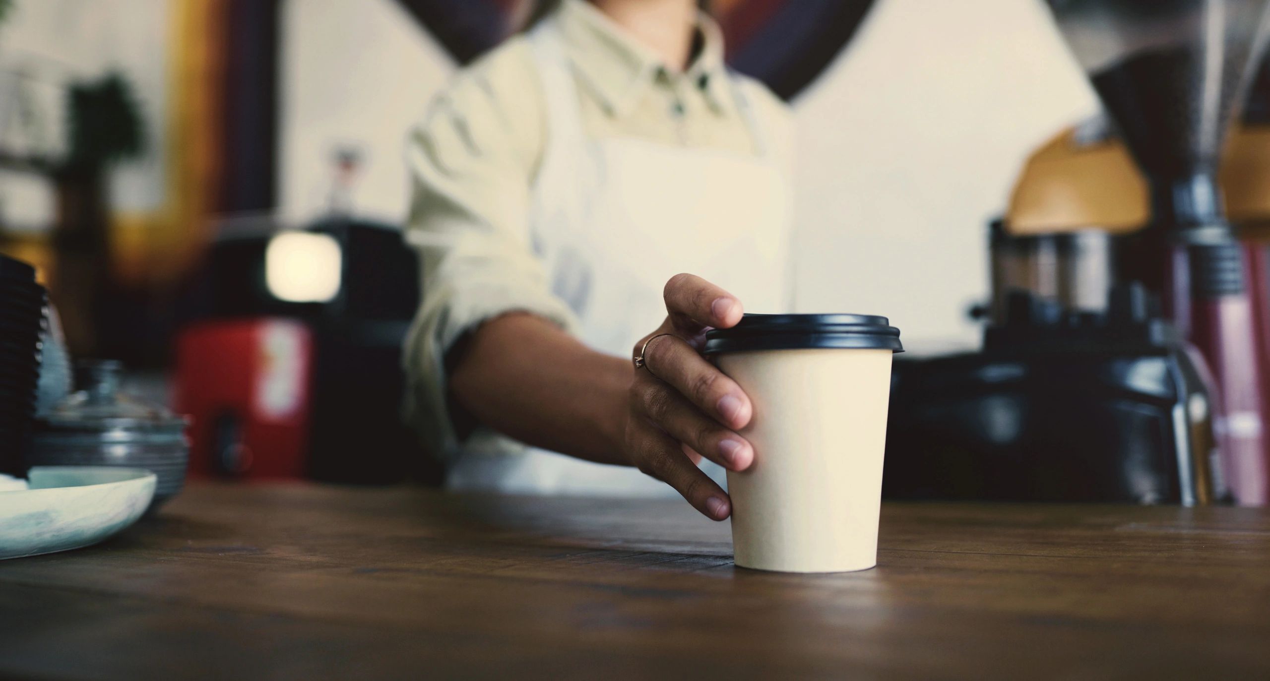 Hands holding a takeaway coffee cup at a counter