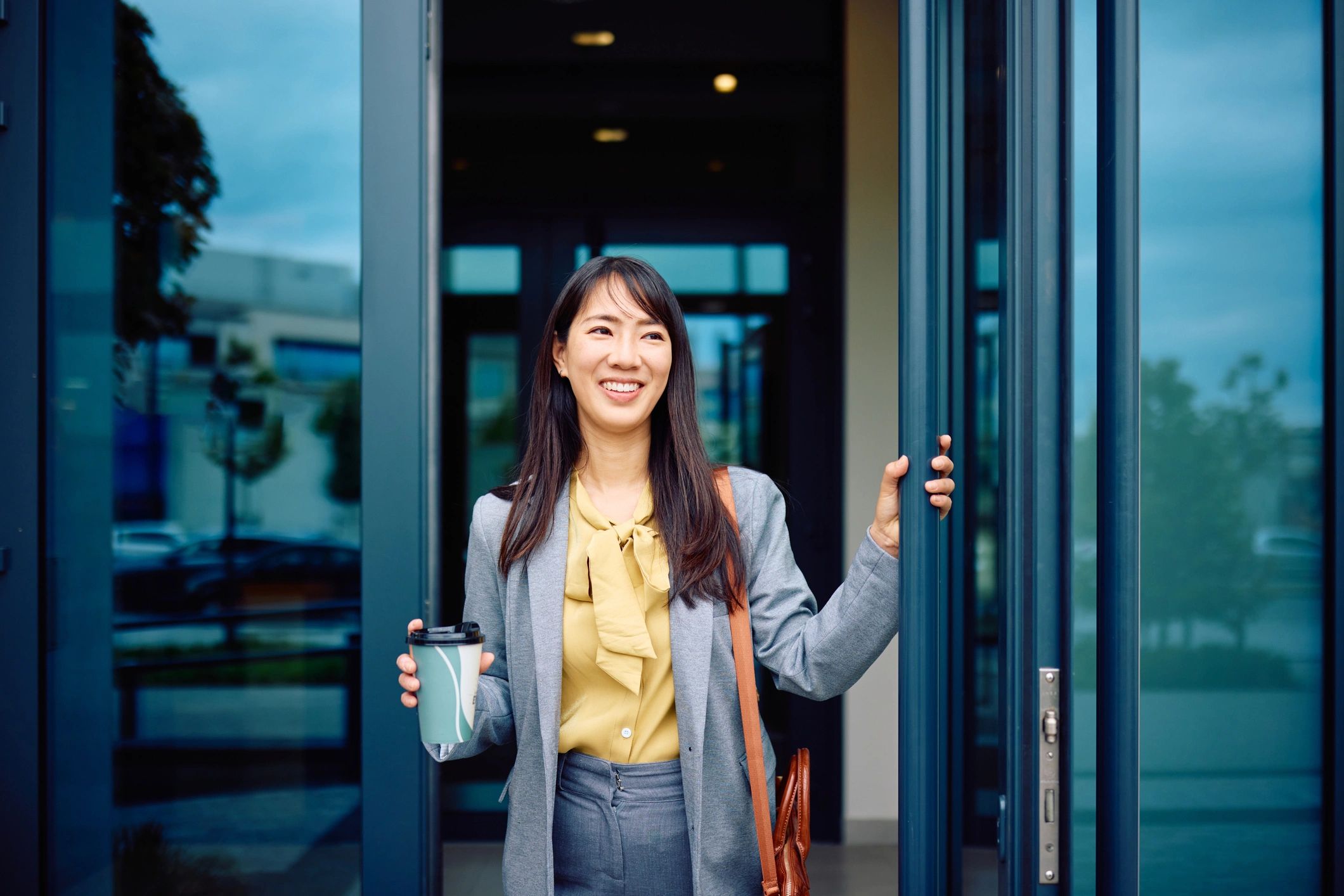 Person holding a takeaway coffee cup while heading into work