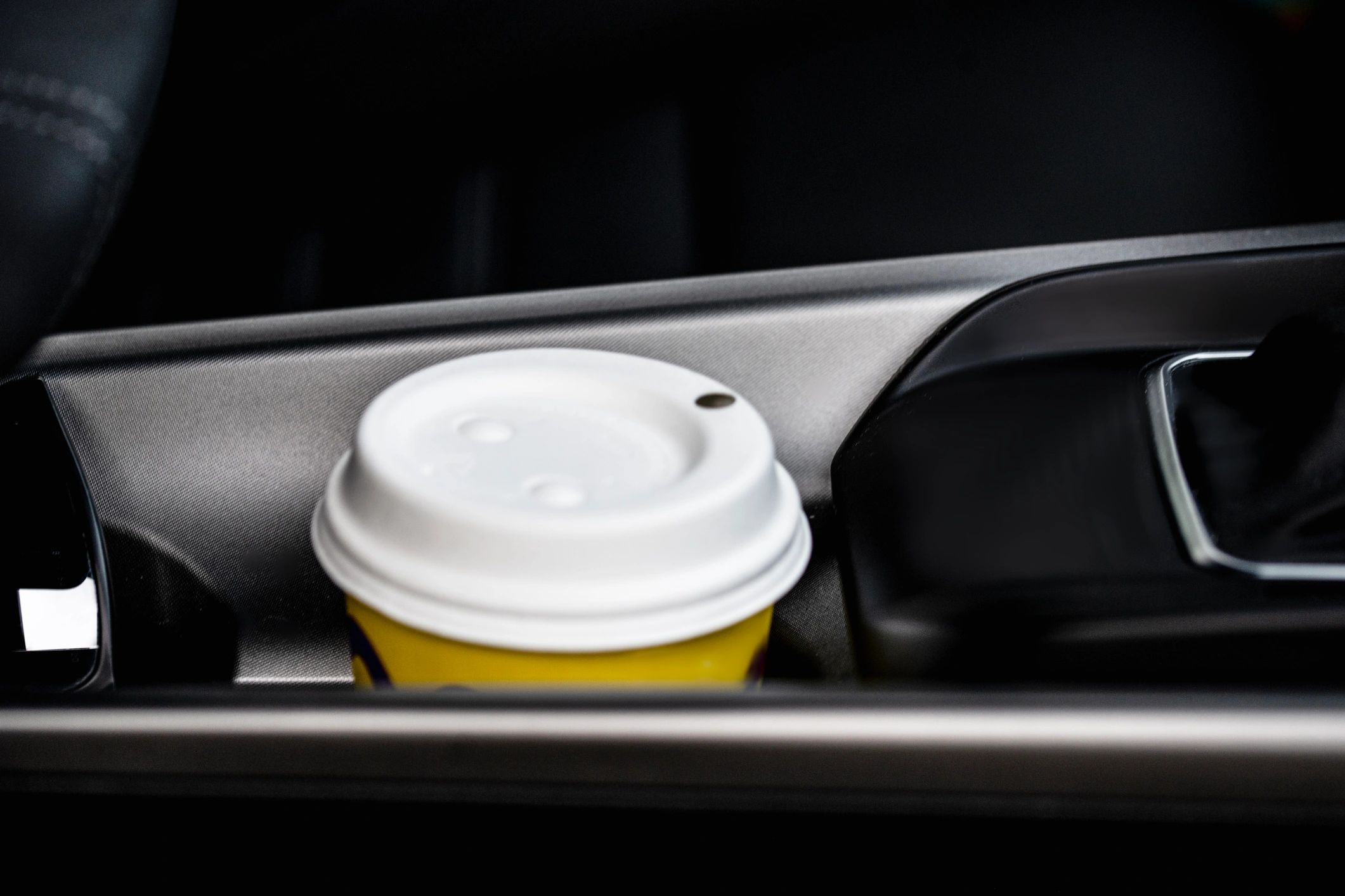 Close-up of a to-go coffee cup with lid in a car cup holder